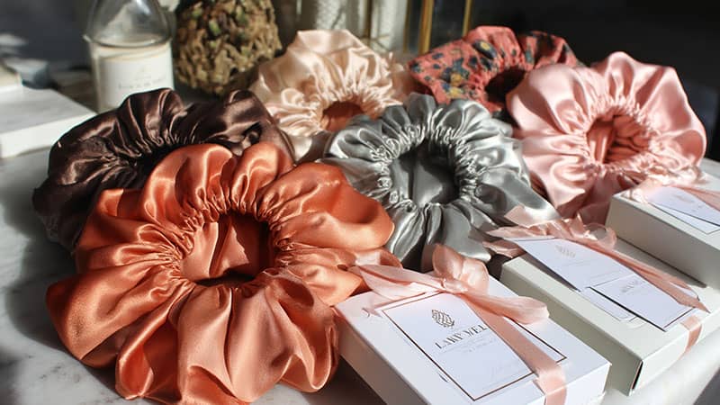 Branded silk bonnets in various colors with custom embroidery and packaging, ideal for personalized and private label orders.