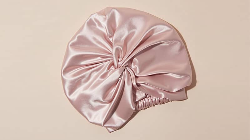 Top view of a luxury mulberry silk bonnet on white background, showcasing smooth texture and quality craftsmanship for hair care.