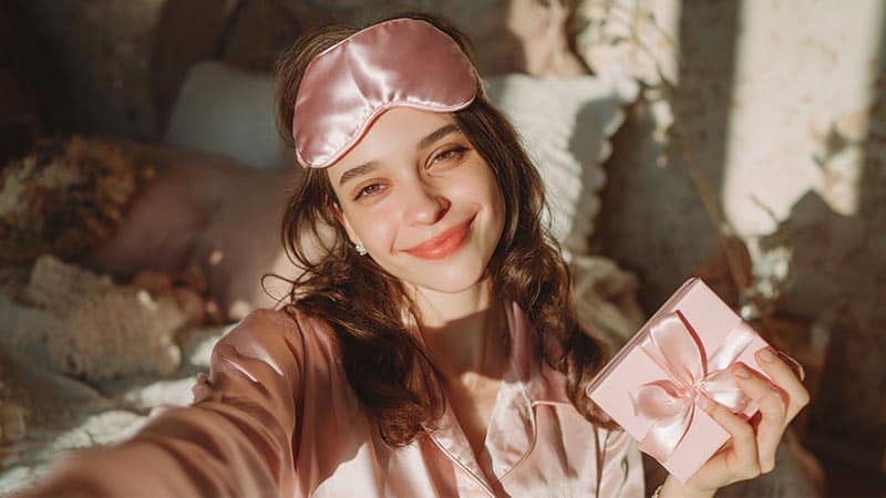Influencer sharing silk eye mask gift set on social media, promoting beauty sleep and wellness product
