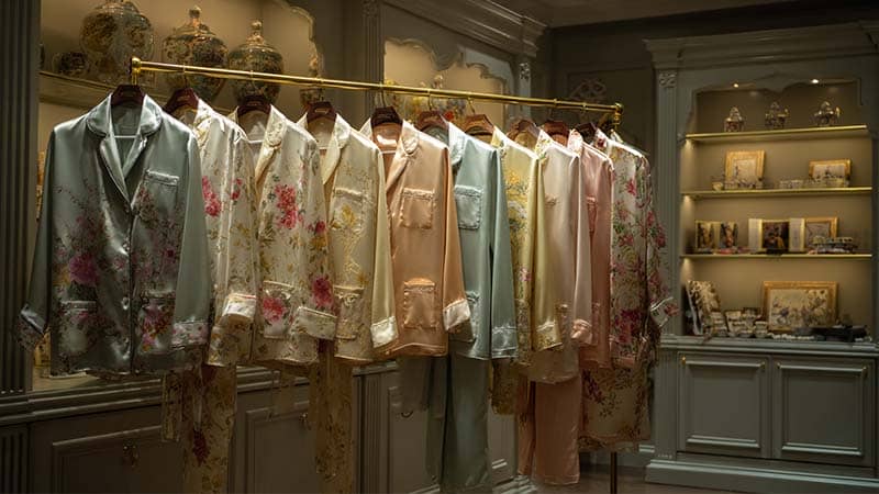A variety of high-quality silk pajamas including mulberry silk pajamas, imitation silk pajamas, embroidered silk pajamas, and printed silk pajamas displayed in a luxury boutique.