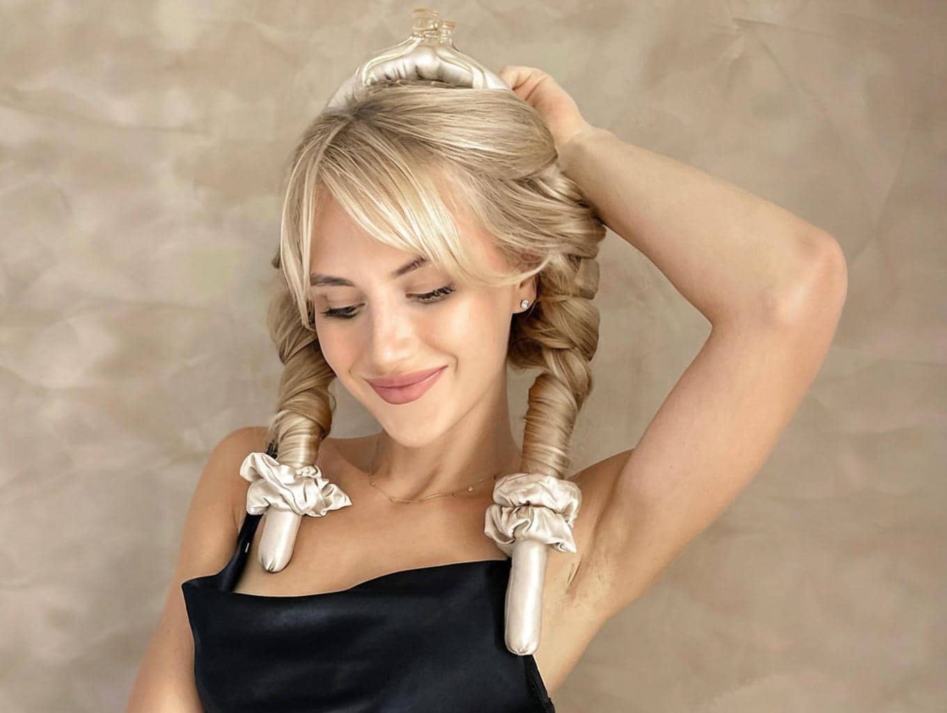 Woman with short hair using silk heatless hair curler in a bedroom setting