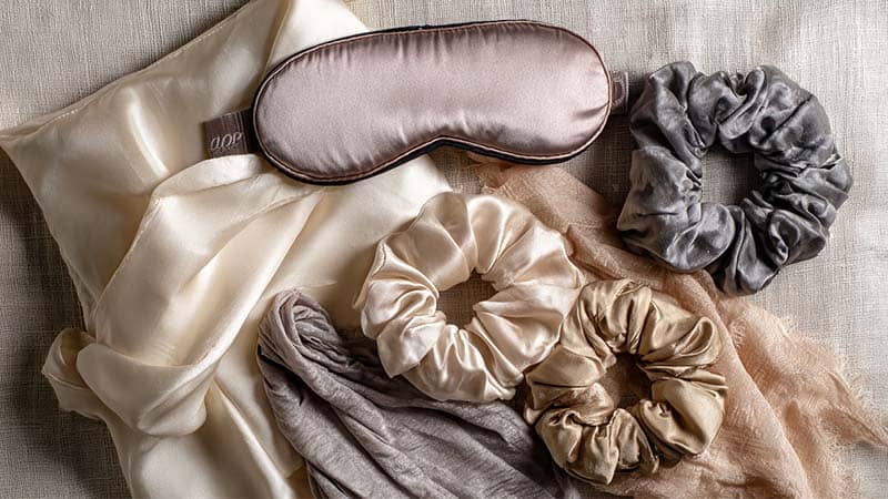 Assorted silk products showing use cases—mulberry silk pillowcase, silk pajamas set, pure silk eye mask, silk hair scrunchies, and peace silk scarves—highlighting texture and applications.