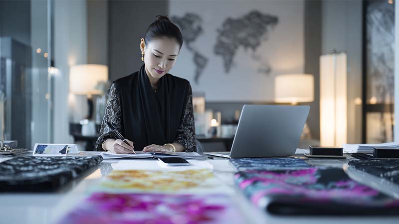 Brand owner reviewing silk product designs and contracts with a Chinese silk factory partner, discussing how to protect silk product designs and brand identity.
